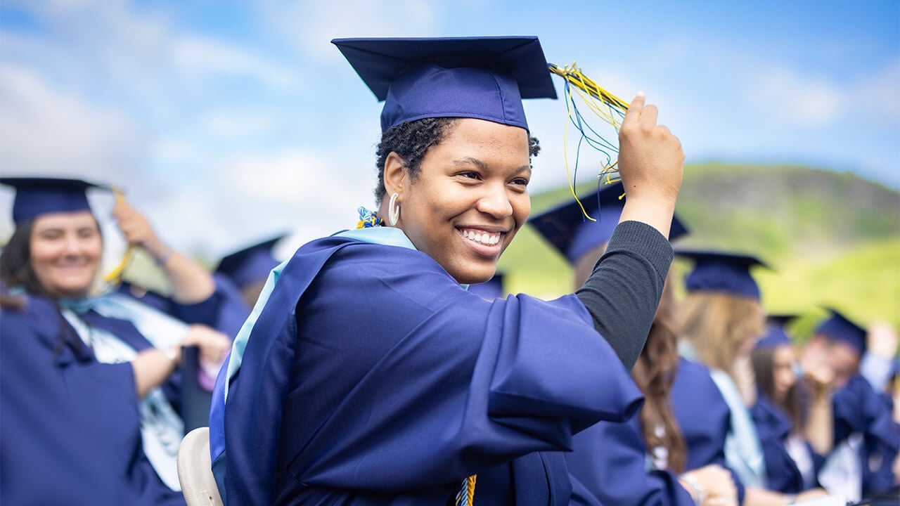 Student in cap and gown moves tassel.