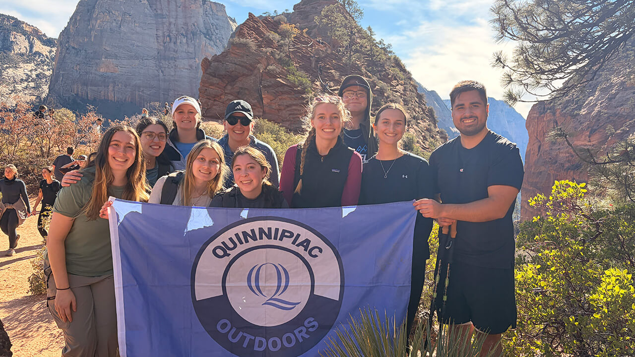 Quinnipiac students hold QU Outdoors flag